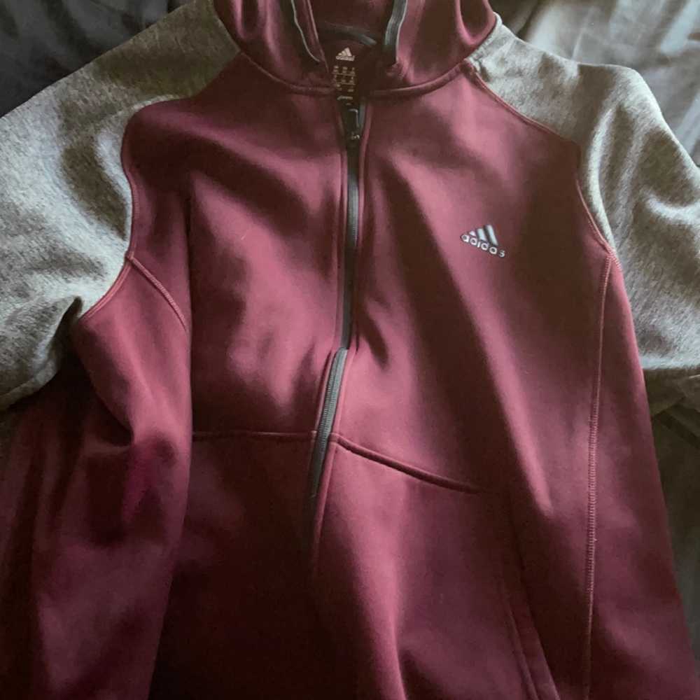 A zip up jacket with hood and the brand is adidas